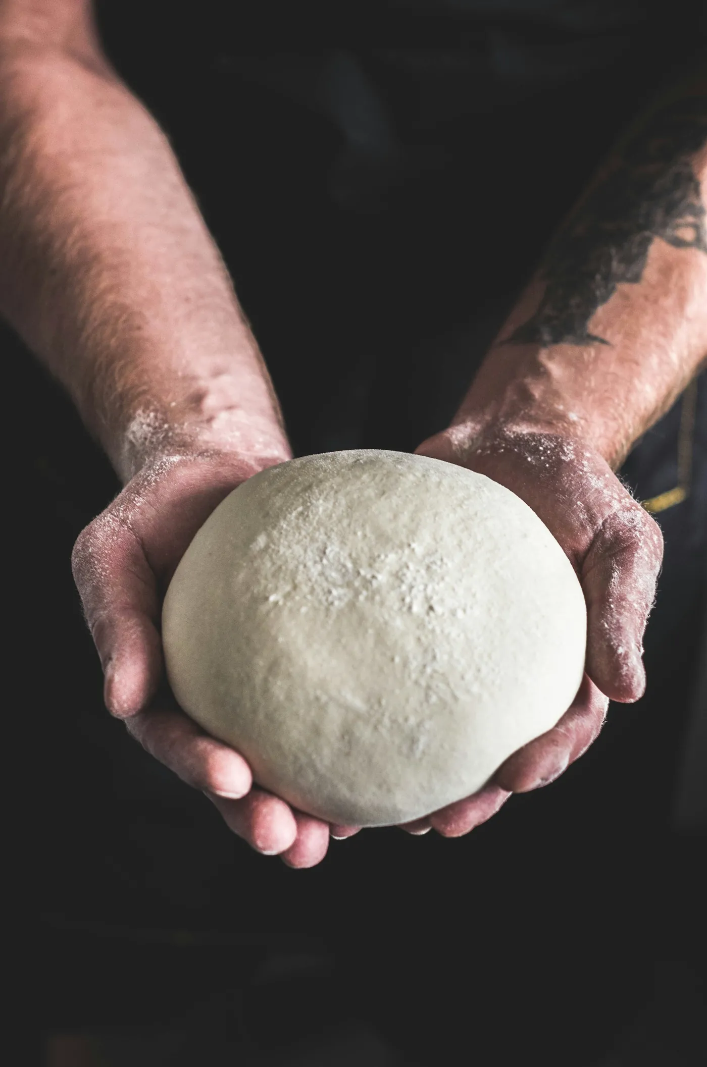 Bola de masa de pizza en las manos