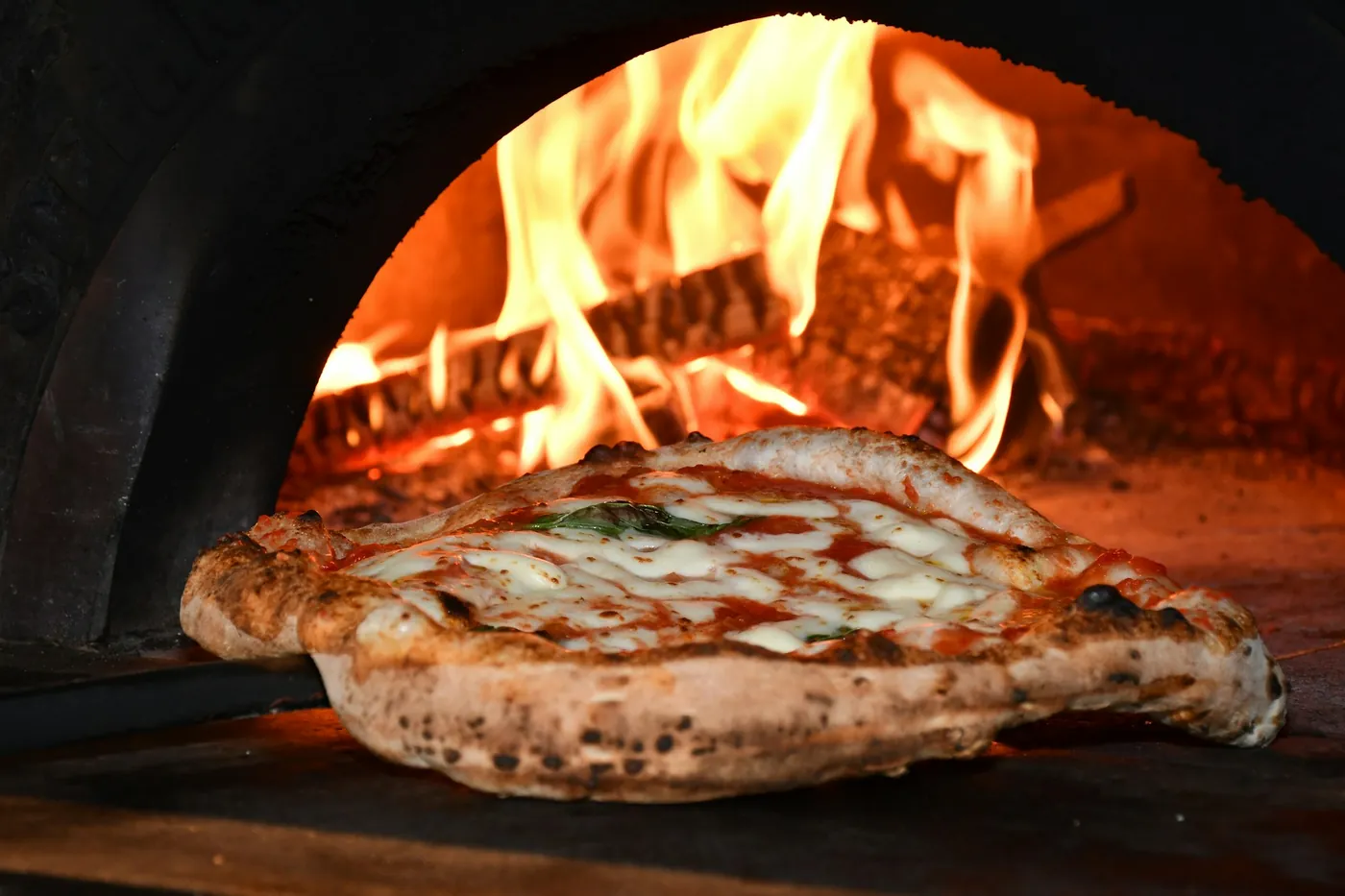 Pizza horneándose en el horno de leña